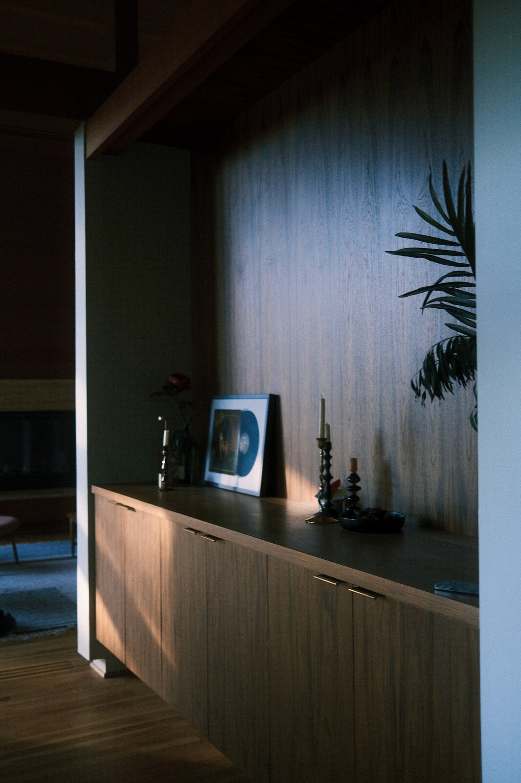 The grain-matched teak wall and sideboard in the dining room, in low light.